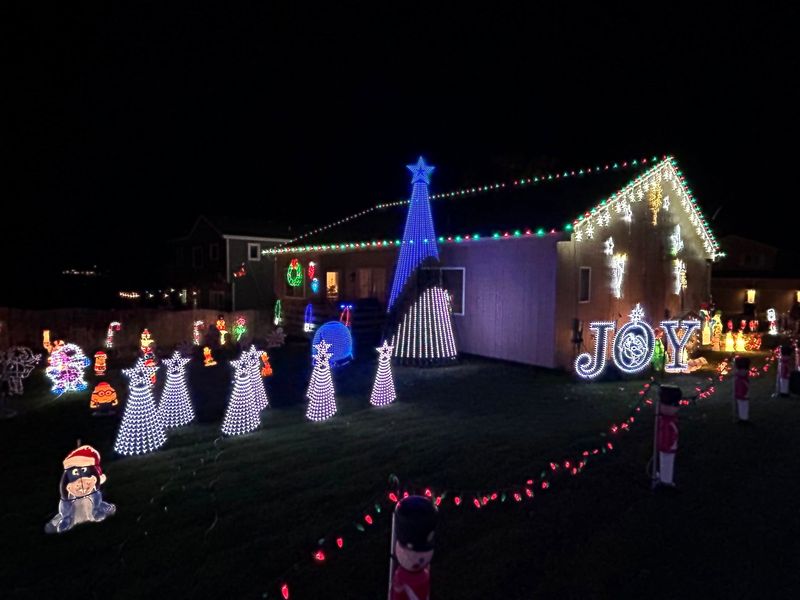 The mega tree and JOY sign with white cone trees across the lawn